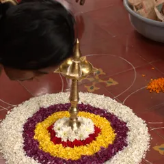 A staff member carefully creates a 'Pookalam', a traditional floral carpet, for Onam. The intricate design and vibrant colors symbolize prosperity, harmony, and a warm welcome to all.