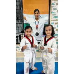 Two young girls in their Taekwondo uniforms, ready to train. Our classes provide a great space for kids to make new friends.