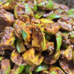 A close-up of the mango pickle preparation. The combination of green mango skin and yellow flesh with dark spices looks as good as it tastes.