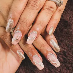 An elegant and sparkly design. This set features coffin-shaped nails with a mix of full-coverage gold glitter and abstract white and glitter art.