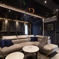 Another view of the home theatre, showing the dark, moody color palette and curved wall design that minimizes light reflection and enhances the viewing experience.