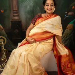 A joyful, candid moment captured during our traditional saree photoshoot. The mother-to-be's smile is infectious as she cradles her bump, seated elegantly in her beautiful attire.