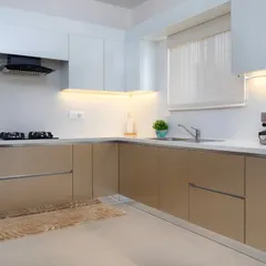 A wider view of the two-toned kitchen, showing the seamless, handle-less cabinetry and the efficient L-shaped layout. The design is clean, modern, and practical for daily use.