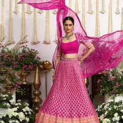 The sheer organza dupatta of this fuchsia lehenga floats gracefully, adding a layer of dreamy elegance. Its movement highlights the rich texture of the Bandhani skirt, creating a captivating silhouette.