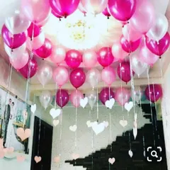 A soft and romantic balloon ceiling decoration perfect for anniversaries or birthdays. This setup uses shades of pink and white, with hanging paper hearts that add a sweet, delicate touch to the room.