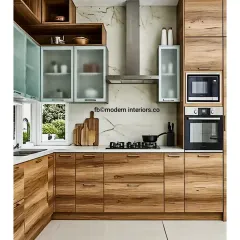 This L-shaped modular kitchen features a beautiful combination of natural wood finish and frosted glass cabinets. The layout is designed for efficiency, with a dedicated tower for a built-in oven and microwave.