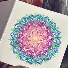 This brightly colored mandala showcases a rainbow gradient, blending from warm pinks and oranges to cool blues and greens. It's a cheerful piece drawn in my sketchbook, full of energy and detail.