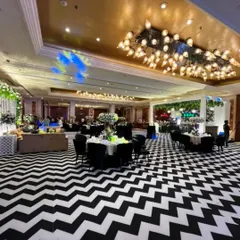 A full view of a banquet hall we transformed for a formal corporate dinner. The striking black and white chevron flooring, combined with elegant black seating and lush white floral centerpieces, created a sophisticated and modern ambiance for the entire event.