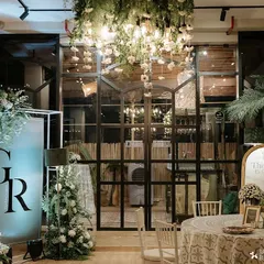 A wide view of a chic and modern wedding reception. We used a custom monogrammed light box, dramatic floral installations, and a floating greenery chandelier to transform the industrial-style venue into a romantic haven.