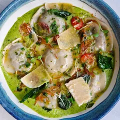A bowl of my vibrant green ravioli, filled with deliciousness and topped with parmesan shavings. It's mischief and mouthfuls, all in one.