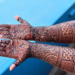 A full-coverage design that extends up the arm, photographed against a bright blue background to make the details pop. This is a great option for sangeet or reception parties.