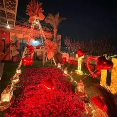 A breathtaking outdoor proposal or romantic dinner setup. A path of red rose petals and lanterns leads to a beautifully decorated canopy tent under the stars.