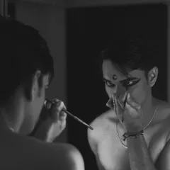 Another black and white shot of the makeup process. The mirror reflects the transformation from person to performer.