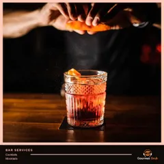 Sit back and relax while we handle the party, from the food to the bar. This image captures a bartender adding the final orange peel garnish to a classic cocktail.