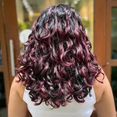 This vibrant Cherry Cola look was achieved with a no-bleach balayage. It’s a fantastic way to add a pop of rich red to dark hair while keeping curls juicy and defined.