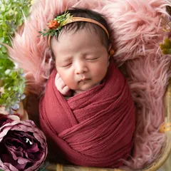 There is nothing more precious than a sleeping newborn. I specialize in safe newborn posing, and this little one, nestled among flowers in a deep red wrap, shows the peaceful, dreamy art we can create in those first few weeks.