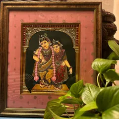 A beautiful framed painting of Radha and Krishna. For this piece, we tried a new kind of frame with a peach-colored silk cloth to add to the romanticism of the divine couple.