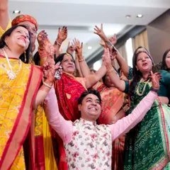 A moment of pure joy and celebration during the Mayra ceremony. The brother of the bride is surrounded by dancing family members, all with their hands in the air.