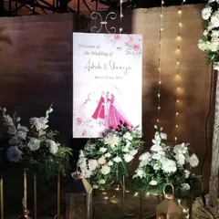 A personalized welcome sign featuring a lovely caricature of the bride and groom, surrounded by elegant white floral arrangements.