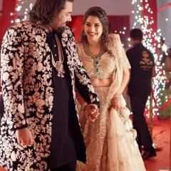 For this joyous occasion, I designed a custom black sherwani jacket featuring intricate, contrasting floral embroidery. It creates a powerful yet elegant statement, perfectly harmonizing with the bride's golden lehenga for a stunning couple's entrance.