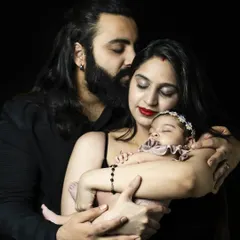A beautiful, intimate black and white portrait of new parents lovingly holding their newborn baby, capturing the emotion of early family life.