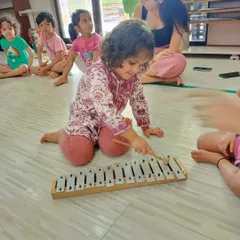 A young student in our Bandra workshop tries out a metallophone, carefully striking the keys. We encourage individual exploration of instruments to help children discover different sounds and melodies.