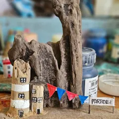 A work-in-progress shot of another driftwood piece, this one celebrating a little slice of paradise. You can see the unpainted wood and the tiny details, like the hand-painted banner, that come together to create these miniature scenes.
