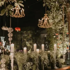 A dreamy night-time setup featuring tall candles amidst clouds of baby's breath, with elegant wooden chandeliers hanging overhead.