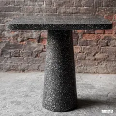 A beautiful and robust terrazzo cafe table with a solid pedestal base. Its dark, speckled finish provides a durable and stylish surface perfect for high-traffic commercial environments like cafes and restaurants.