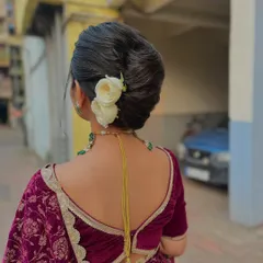 This clean, classic bridal bun is adorned with simple white roses. It's an understated and elegant take on the traditional khopa, ideal for a bride who prefers a minimalist yet timeless look for her wedding day.