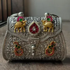 This is where tradition meets trend. A close-up of our bespoke fusion clutch, featuring intricate silver filigree work with gold plating and colourful stone embellishments like camels and paisleys. It’s a statement piece that tells a story.