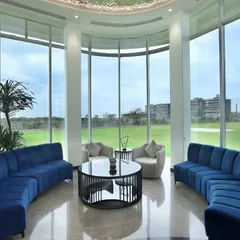 This spacious lounge area features floor-to-ceiling curved windows that flood the space with natural light. The deep blue sofas provide a bold color contrast, creating a modern and inviting space for residents to relax and socialize.