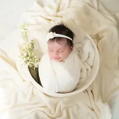 A peaceful newborn portrait, styled with delicate baby's breath flowers and soft, cream-coloured fabrics for a pure and angelic look.