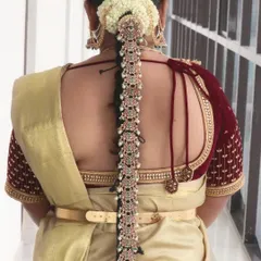 A classic South Indian bridal hairstyle. This long braid is adorned with beautiful kemp stone jewelry and fresh jasmine, a timeless choice for any traditional bride.