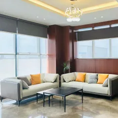 This waiting area for an MD's room features contemporary sofas with clean lines and pops of color from the throw pillows. The recessed ceiling with a modern chandelier creates a sophisticated and well-lit space.