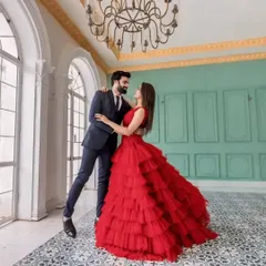 For that perfect pre-wedding shoot, I offer coordinated couple outfits. This dramatic red layered gown and complementary men's suit create a stunning visual, making your photos truly unforgettable.