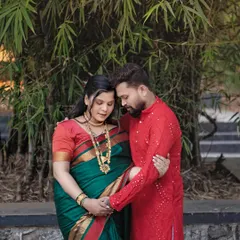 An intimate couple's pose set against a natural bamboo background. This traditional pregnancy portrait focuses on their connection, with their hands joined over her baby bump.