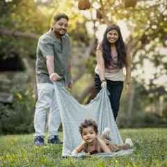 A family plays together in a park, with the parents pulling their toddler along on a blanket. This image perfectly captures the fun and candid spirit of my outdoor sessions.