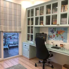 A functional and stylish study area integrated into a bedroom. The custom cabinetry provides ample storage, while the desk overlooks a balcony, providing natural light and a refreshing view.