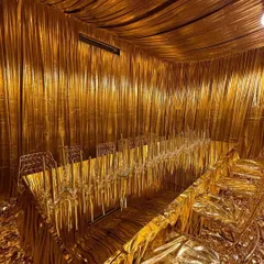 An alternate view of the all-gold dining room, showcasing the complete transformation. The metallic fabric drapes the ceiling and walls, creating a seamless, shimmering cave of opulence for an unforgettable dining experience.