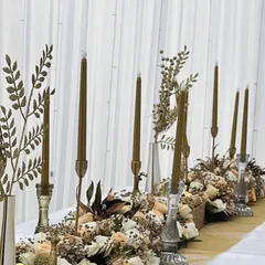 This shot highlights the tall, golden candles and metallic foliage we incorporated into the floral table runner. The varying heights add visual interest and a warm, flickering glow to the dining experience.