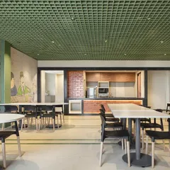 The cafeteria at the Bestseller office, featuring a playful wall mural and a green grid ceiling. The design creates a casual, vibrant, and energizing atmosphere for employees to relax and recharge.
