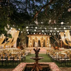 The full view of an outdoor Sangeet, with golden drapes, fairy lights, and elegant round table seating. We design the layout to ensure a great view for all guests and plenty of space for dancing.
