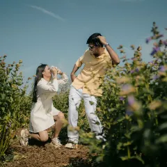 A playful and quirky moment captured in the field. This shows that pre-wedding shoots can be fun and full of personality, reflecting the couple's unique dynamic.