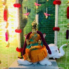 For this Varamahalakshmi pooja, the deity is seated on a decorative white elephant. The background features our traditional woven leaf mat with hanging floral strings, creating a complete and sacred arrangement.