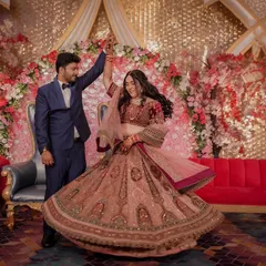 A fairytale twirl during the Sangeet. The groom leads his bride in a dance, her magnificent lehenga spinning around her against a backdrop of lush pink florals.