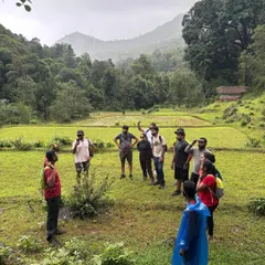 The trek leader briefing the group in a beautiful valley, surrounded by green fields and mountains.