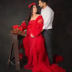 A beautiful couple's portrait filled with love and anticipation. The mom-to-be looks stunning in her red gown, sharing a happy gaze with her partner.
