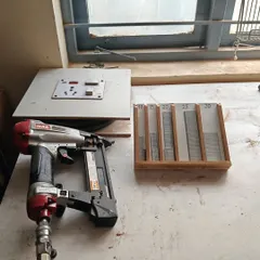 A pneumatic nail gun and a custom-made nail sorting tray. Having an organized workshop and the right tools, like this power carving tray made with a router, makes every project more efficient.