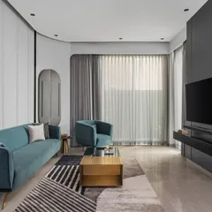 The living room features a bold teal couch against crisp white paneled walls. Minimalist side tables, a textured carpet, and statement decor create a harmonious balance of color, texture, and sophistication.